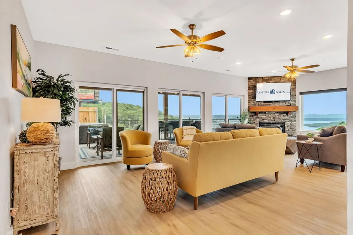 A welcoming living and dining area with cozy seating, a modern stone fireplace, large windows that flood the room with natural light, and decorative plants. The arrangement is ideal for family games, quiet reading, or meals together, all while enjoying the scenic outdoors.