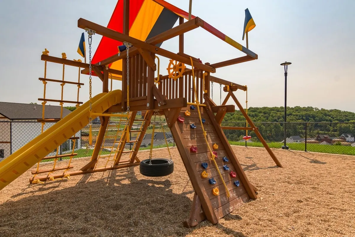 A cheerful playground scene with a vibrant play structure, complete with a climbing wall, slide, and tire swing. Children can be seen playing and laughing, showcasing the family-friendly amenities available at the resort.
