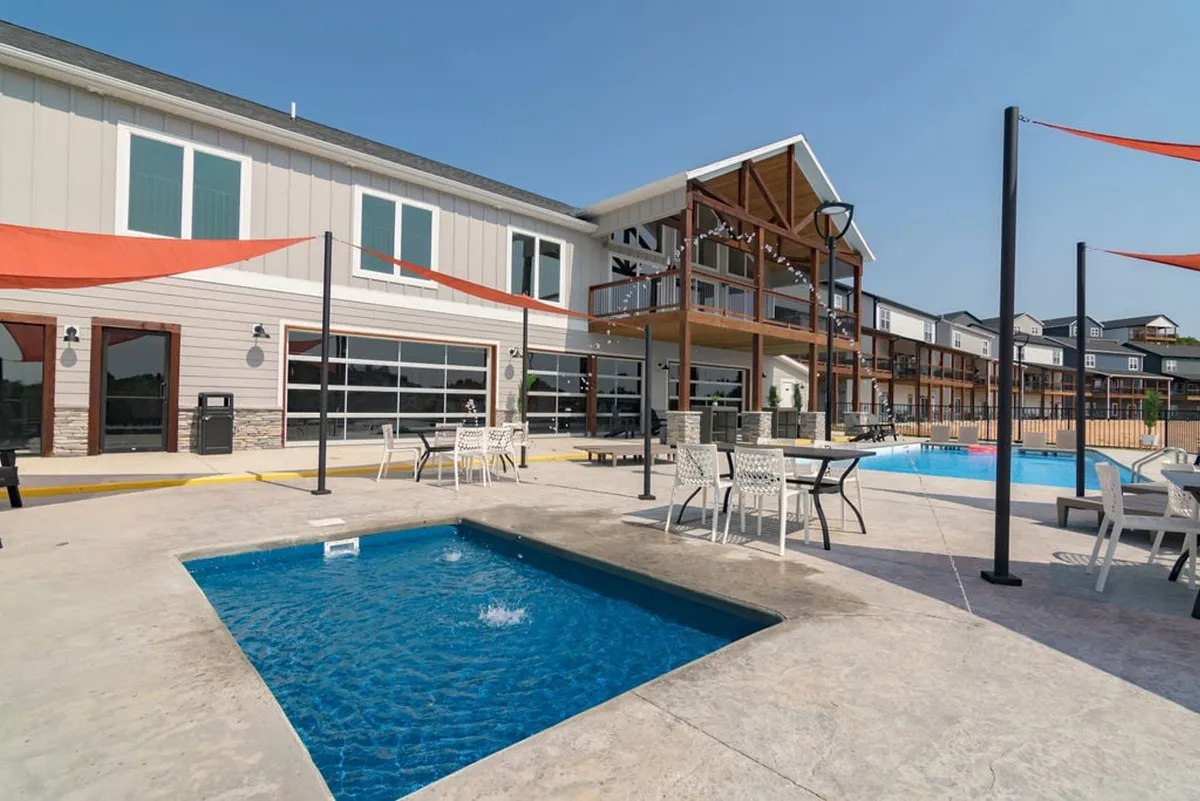 An inviting outdoor pool area featuring a jacuzzi, plenty of comfortable seating, and a view of the lodge’s facade. The setting is perfect for socializing, sunbathing, and group relaxation, ideal for both summer fun and milestone celebrations.